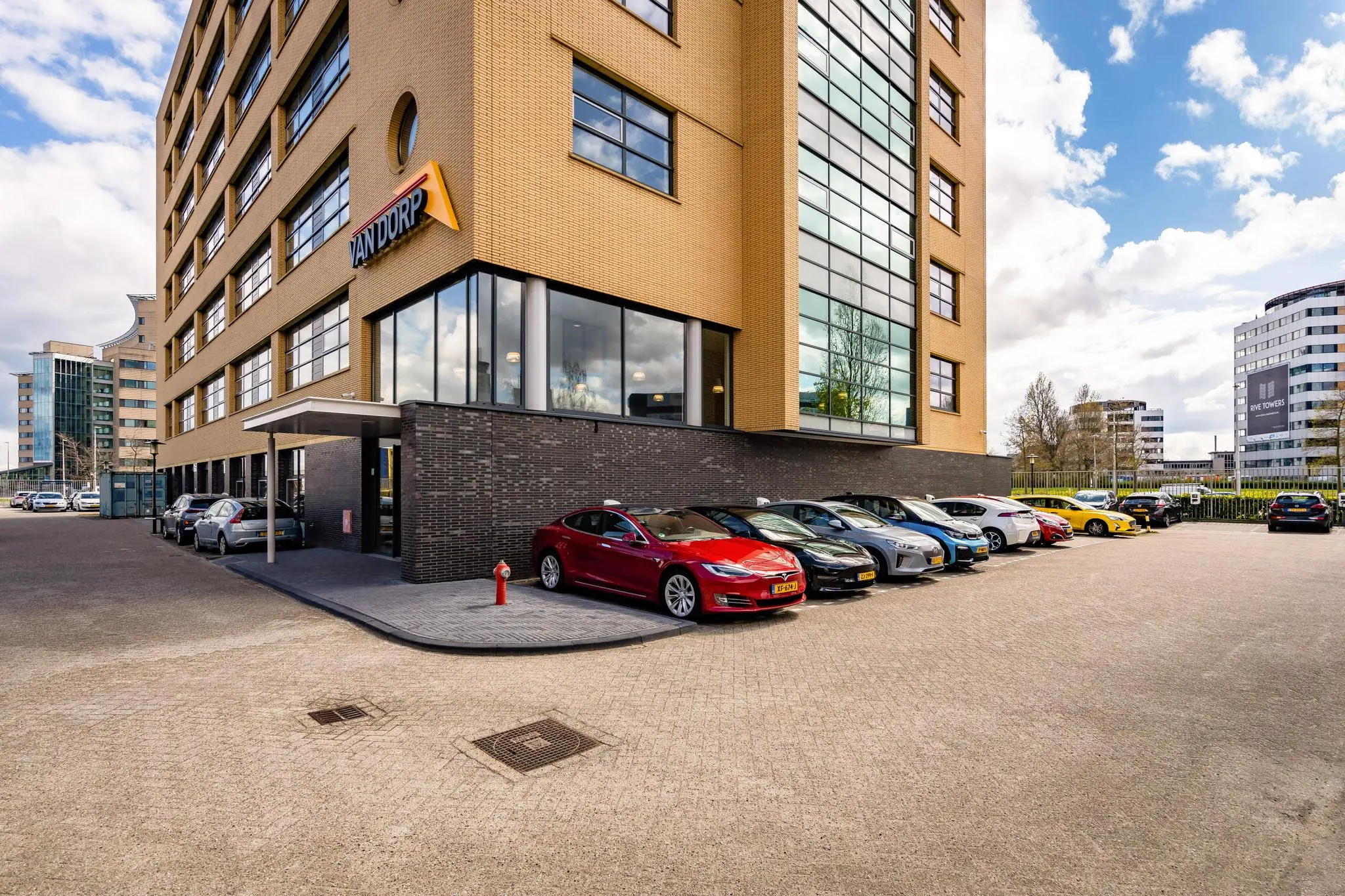 Kantoorgebouw van Van Dorp aan de Fascinatio Boulevard met geparkeerde auto's op de voorgrond.